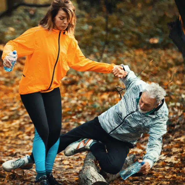 Closeup front view of a senior couple jogging in a forest and having fun.