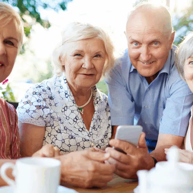 Social Connections for Senior Health Feature Image: Grey-haired senior females and man sitting in outdoor cafe