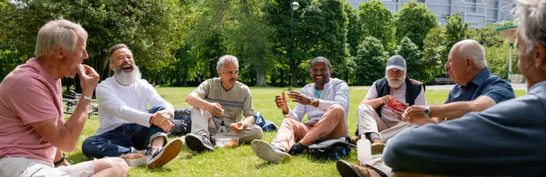A group of senior men relaxing and enjoying a day out in the park together